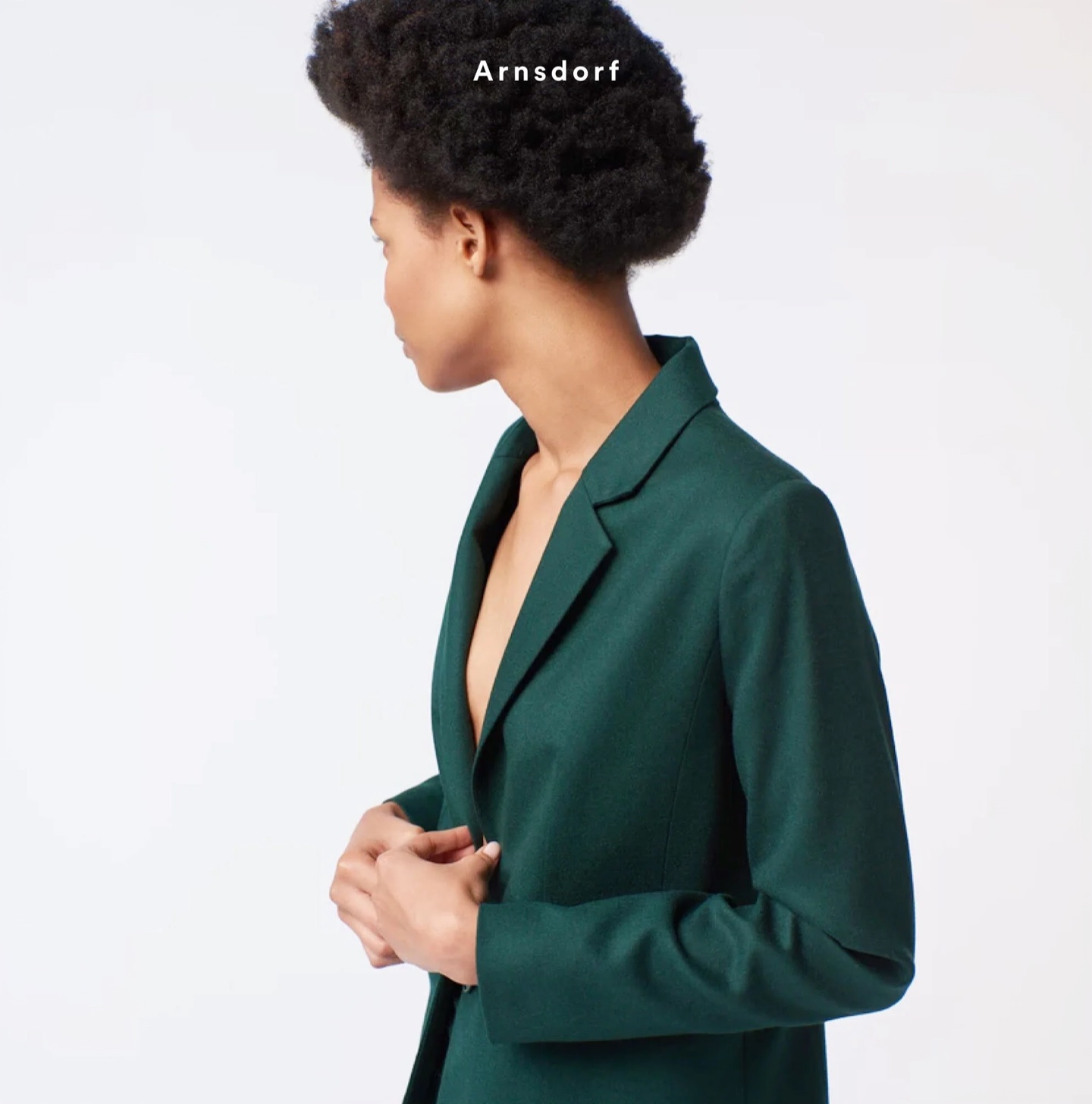 Model in a tailored green Arnsdorf blazer, seen in profile, with the Arnsdorf wordmark above