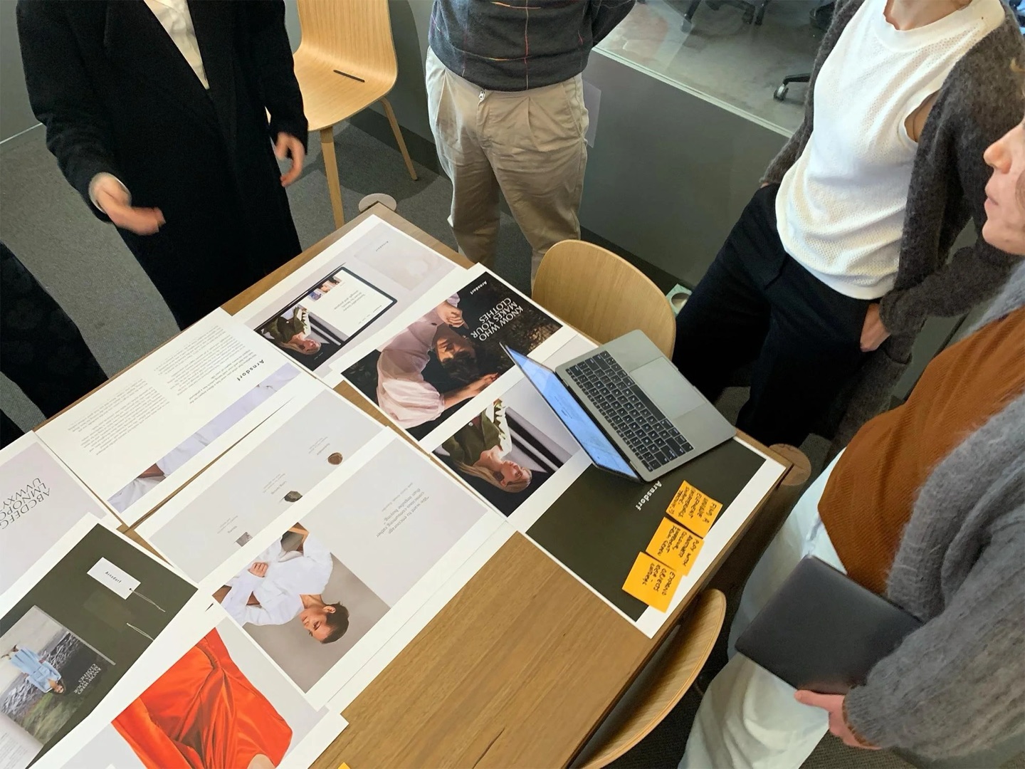 Team reviewing printed Arnsdorf design concepts and sticky notes around a table with a laptop