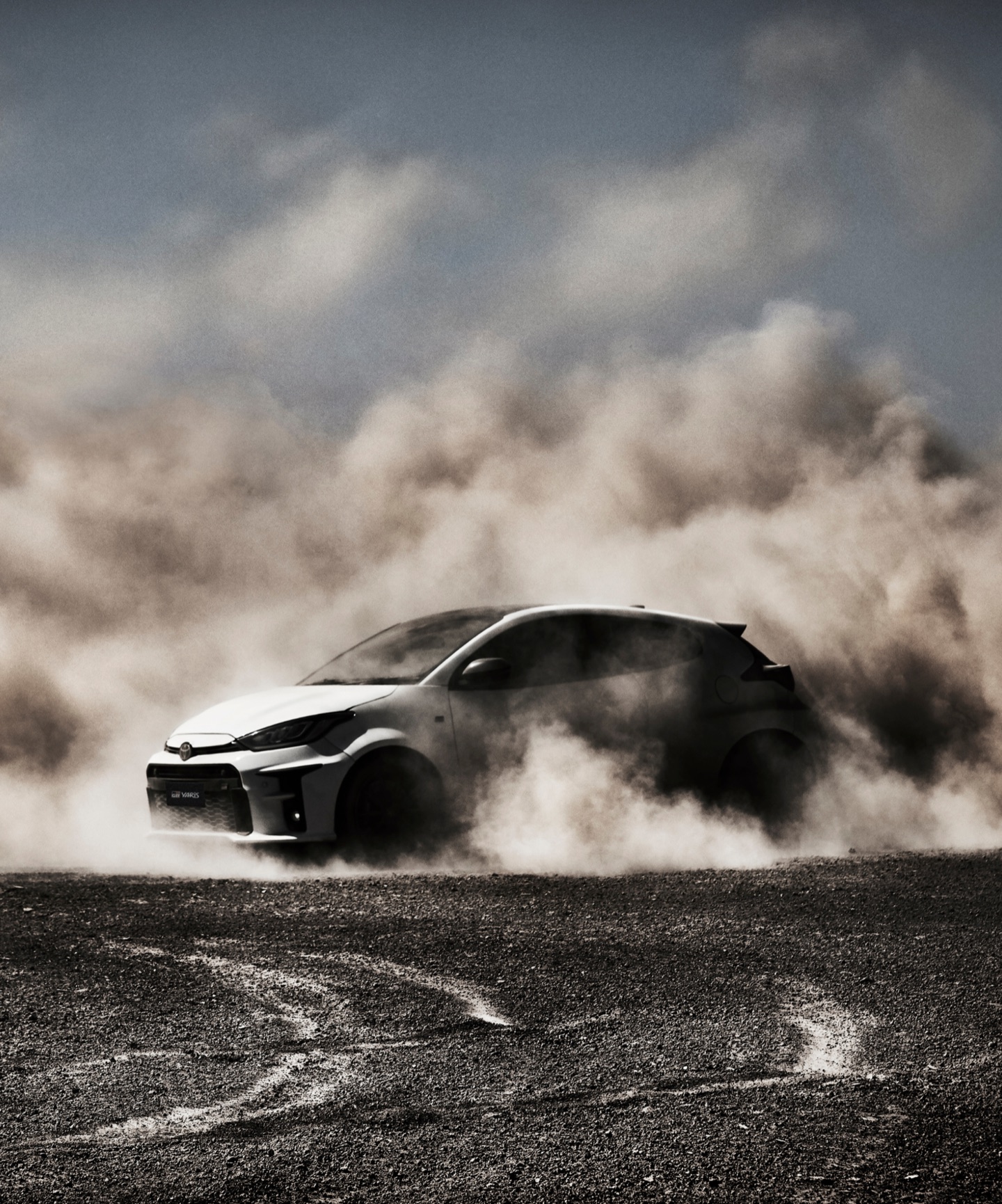 Toyota: white GR Yaris sliding across gravel in a huge cloud of dust