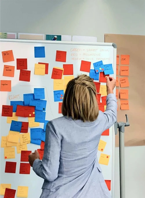 Workshop participant adding sticky notes to a whiteboard during Human Rights Victoria brand research